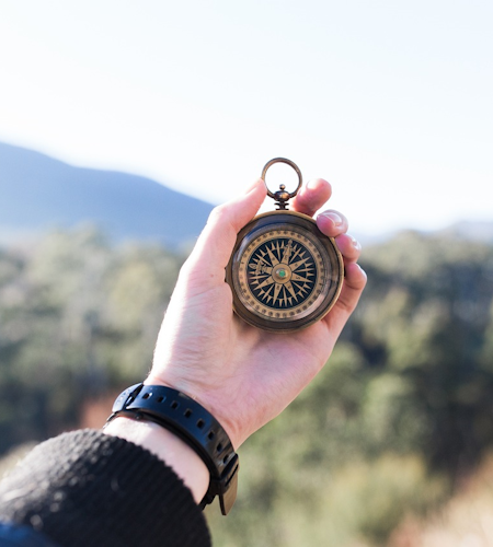 Photo of a hand holding a compass, finding the right direction